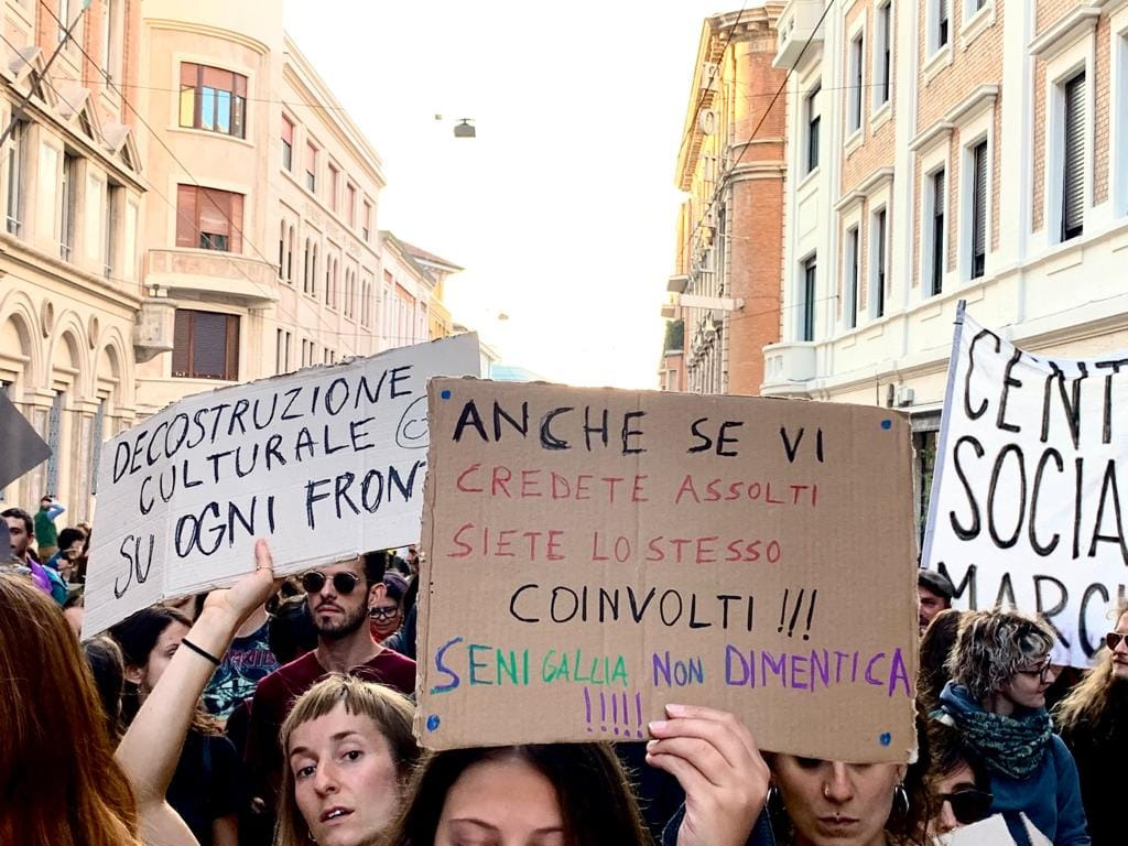 Corteo nel corso di Ancona, si leggono due cartelli. Uno recita "Decostruzione culturale su ogni fronte" e un altro recita "Anche se vi credete assolti, siete lo stesso coinvolti. Senigallia non dimentica!"