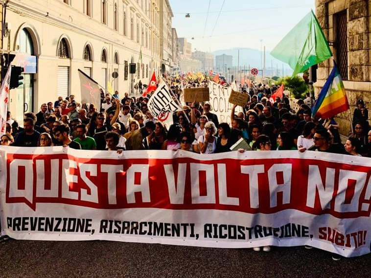 Il corteo sfila sul corso di Ancona. Lo striscione in testa recita "Questa volta no! Prevenzione, ricostruzione, risarcimento subito!"